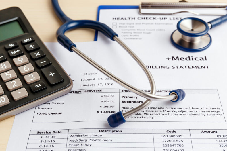 itemized medical bills next to a calculator and stethoscope 